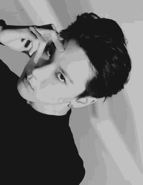 a black and white photo of a young man covering his face