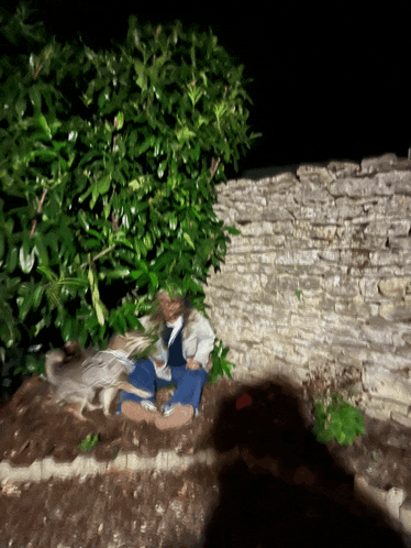 a statue of a man sitting in the dirt with a cat