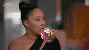 a woman holding a rubik 's cube in front of her mouth