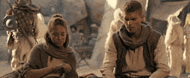 a man and a woman are sitting next to each other in a desert scene