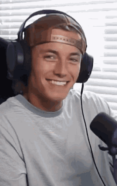 a man wearing headphones and a hat is smiling
