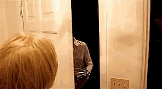 a woman is looking at her reflection in a mirror in a bathroom .