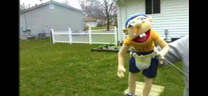 a stuffed animal is standing in the grass in front of a house with a white fence .