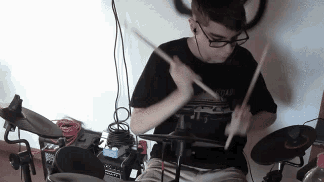 a man playing a drum set with a shirt that says road