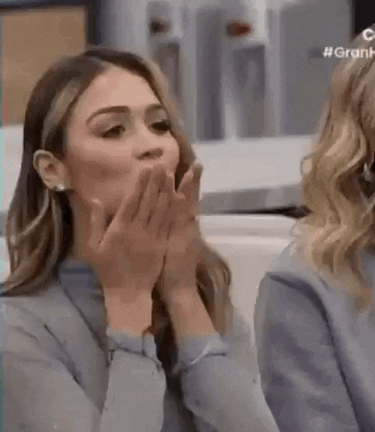 a woman is covering her mouth with her hands while a woman looks on .