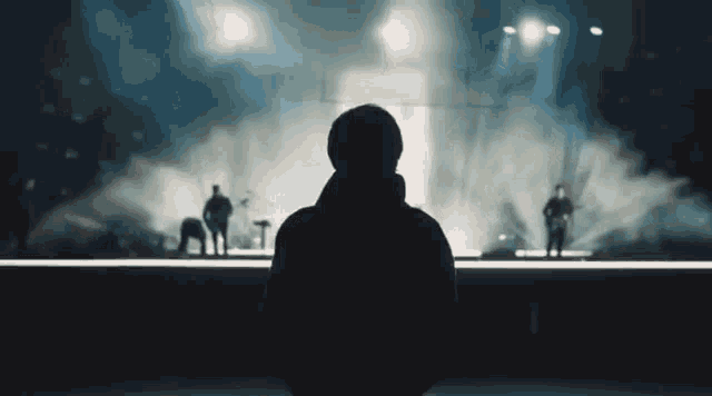 a man is standing in front of a stage watching a band perform on it .