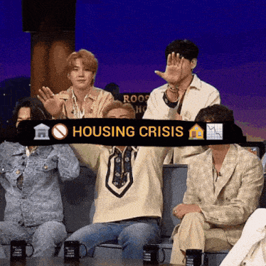 a group of people are sitting on a couch with a sign that says housing crisis