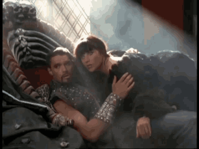 a man and a woman laying on a bed with a skeleton in the background