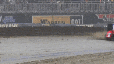 a race car is driving down a track with a cat advertisement in the background