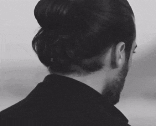 a black and white photo of a man with a bun on his head