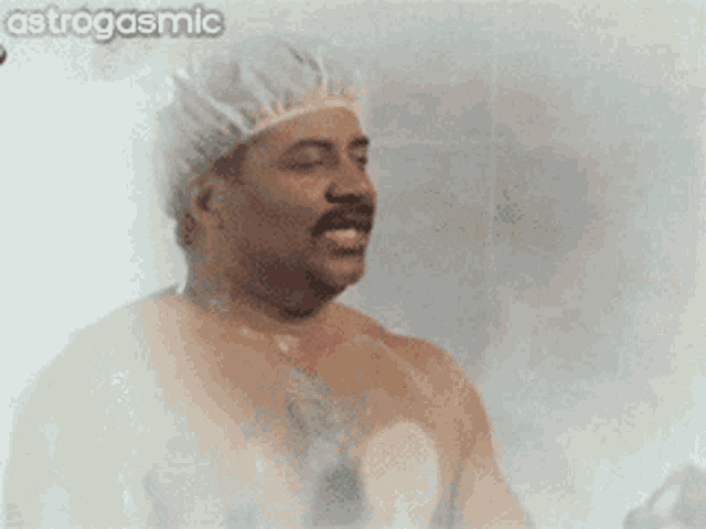 a man taking a shower with a shower cap and a sponge with astrogasmic written in the corner