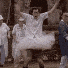a man in a tutu is jumping in the air while a group of people watch .