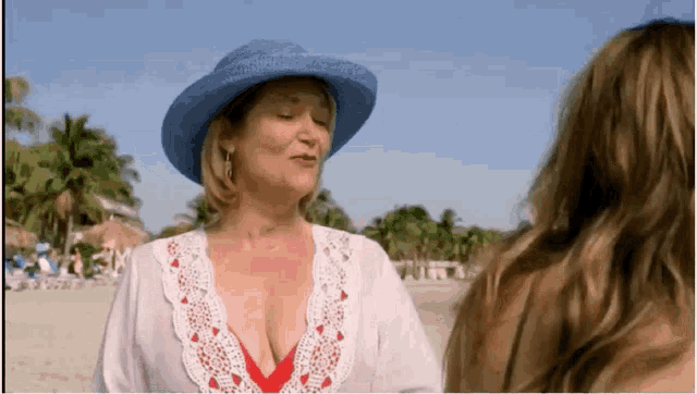 a woman wearing a blue hat and a white shirt stands on a beach