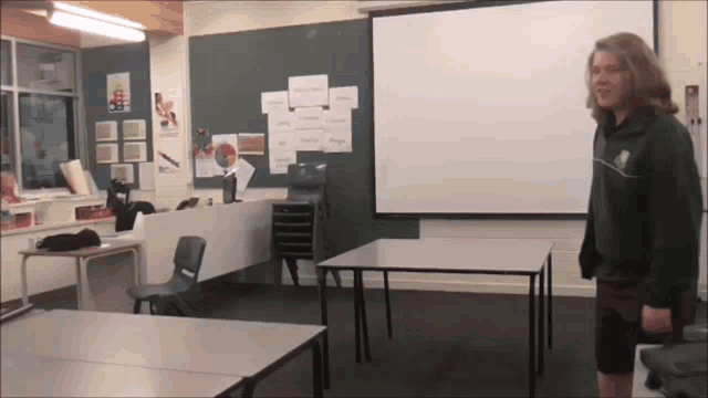 a boy in a classroom with a projector screen