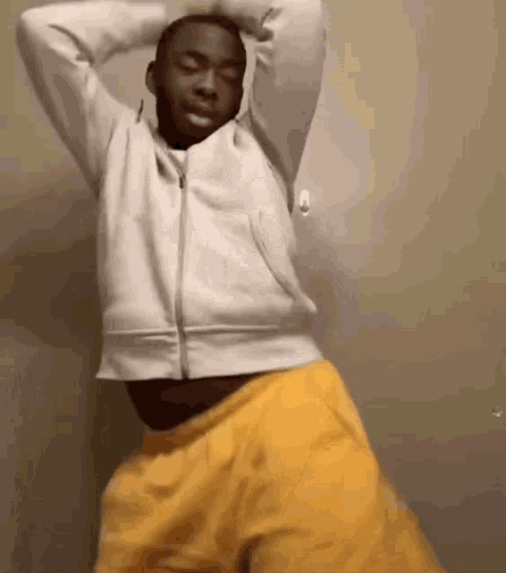 a man in a gray jacket and yellow shorts is dancing .