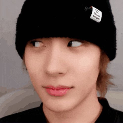 a close up of a person wearing a black beanie with a white label that says i 'm a foreigner