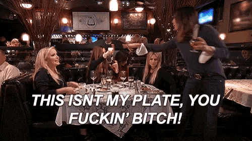 a woman sitting at a table in a restaurant says " this isnt my plate you fuckin bitch "