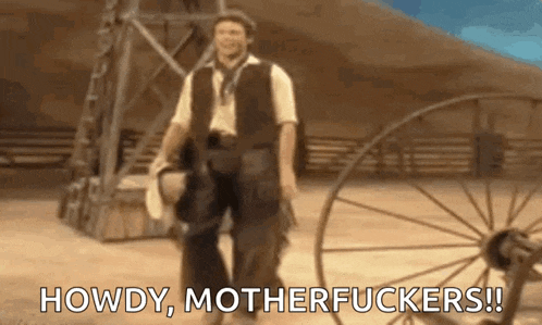 a man in a cowboy outfit is standing in front of a wagon wheel and says `` howdy , motherfuckers ! ''
