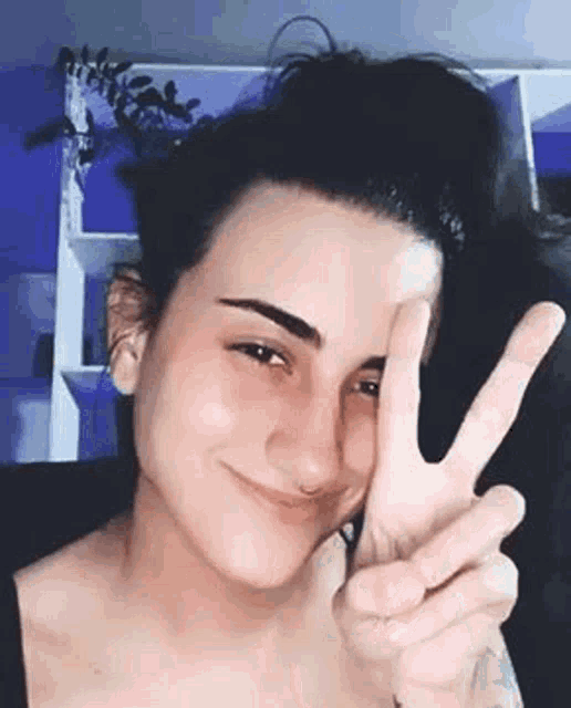 a close up of a woman giving a peace sign .
