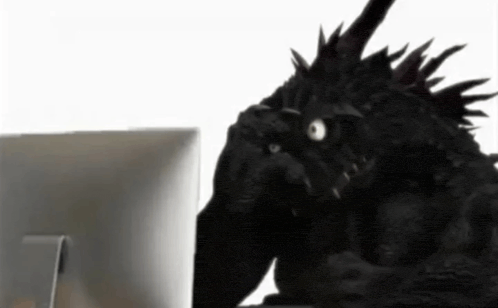 a monster is sitting in front of a computer monitor .