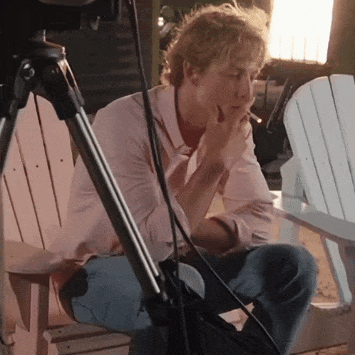 a man smoking a cigarette while sitting on a chair