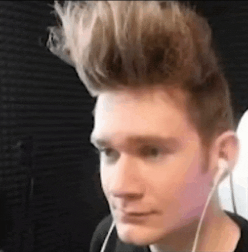 a young man wearing headphones and a mohawk is looking at the camera .