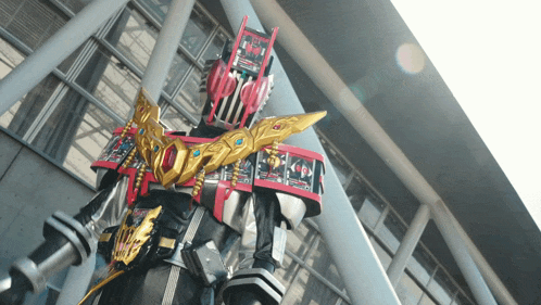 a robot with a red and gold helmet and a sword stands in front of a building