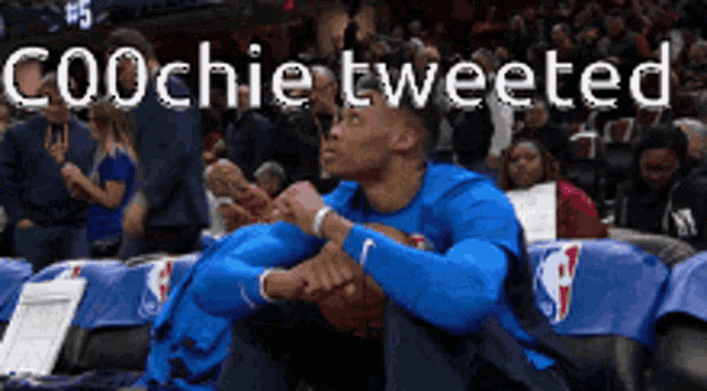 a basketball player is sitting in the stands with the words coochie tweeted behind him