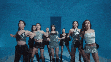 a group of women are standing in front of a blue wall with their arms crossed