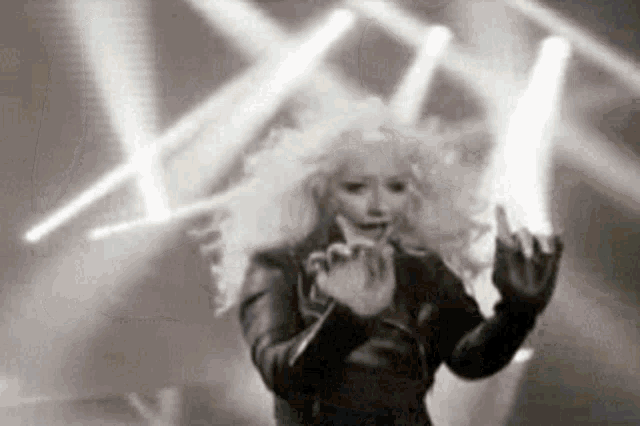 a black and white photo of a woman giving the middle finger while standing on a stage .