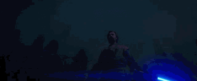 a man is holding a blue light saber in his hands in the dark .