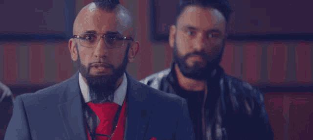 a man with a mohawk and glasses is wearing a suit and tie