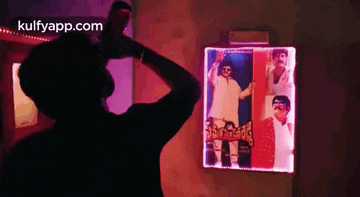 a silhouette of a man standing in front of a wall with a picture of a man on it .