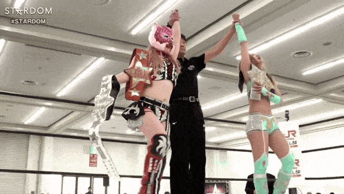 a female wrestler holds up her arms in the air in front of a sign that says stardom