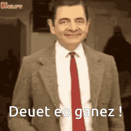 mr bean is wearing a suit and tie and smiling .