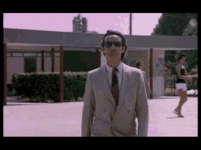 a man in a suit and tie stands in a parking lot