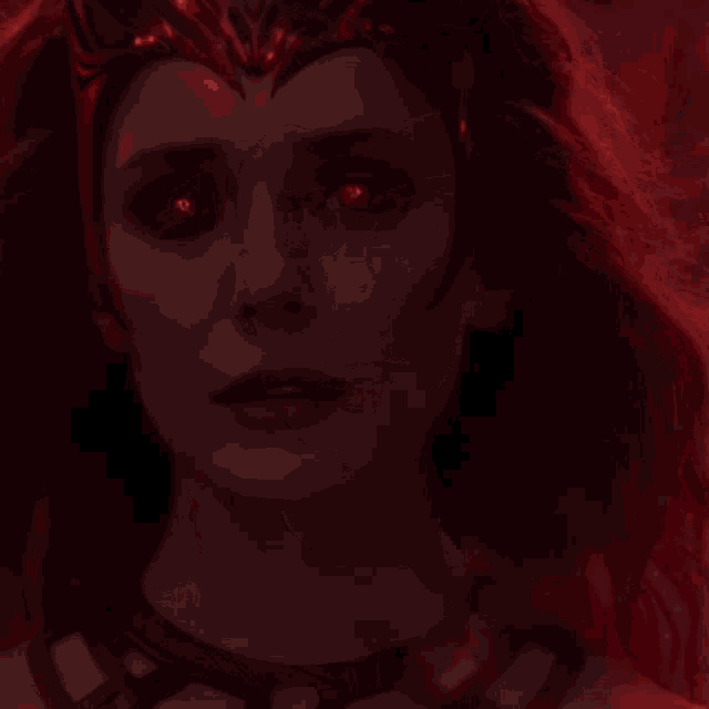 a close up of scarlet witch 's face with red eyes and a crown on her head .