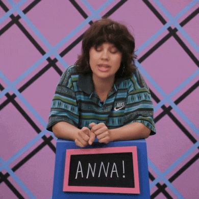 a woman wearing a nike shirt is sitting at a table with a sign that says anna