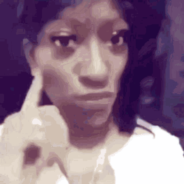 a woman is making a funny face with her finger in her mouth .
