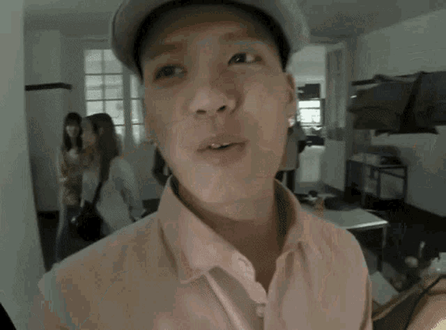 a man wearing a hat and a pink shirt is making a funny face .