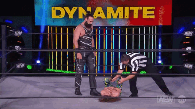 two men in a wrestling ring with dynamite written on the wall behind them