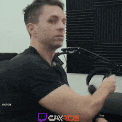 a man in a black shirt is sitting in front of a microphone with a twitch logo in the background