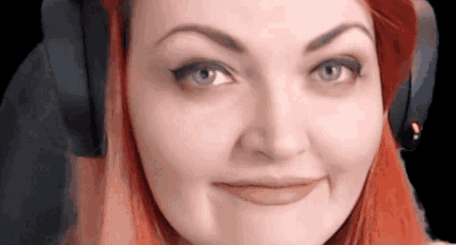 a woman with red hair is wearing headphones and making a funny face