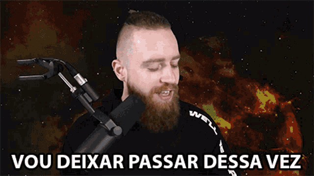 a man with a beard is standing in front of a microphone with the words vou deixar passar dessa vez below him