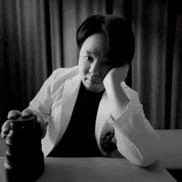 a black and white photo of a woman sitting at a table