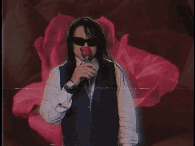 a man wearing sunglasses holds a red rose in front of a pink rose