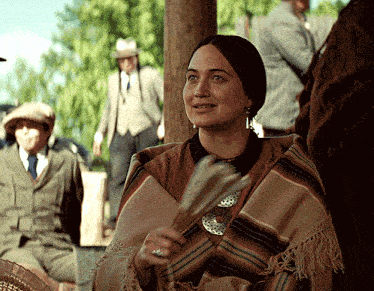 a woman wearing a poncho holds a fan in her hand