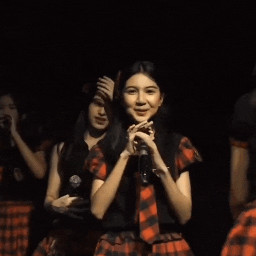 a girl singing into a microphone with a plaid shirt