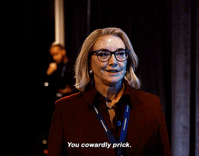 a woman wearing glasses and a lanyard that says you cowardly prick
