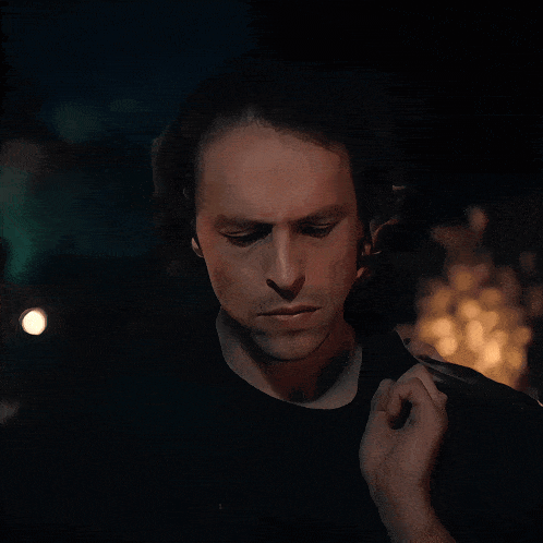 a man in a black shirt looks at the camera in the dark